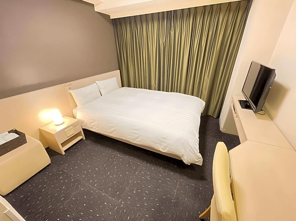 【北見住宿】Dormy Inn Kitami 北見飯店的雙人房，配置一張大床與柔和燈光，房間乾淨明亮、設計簡約，提供舒適的住宿氛圍。