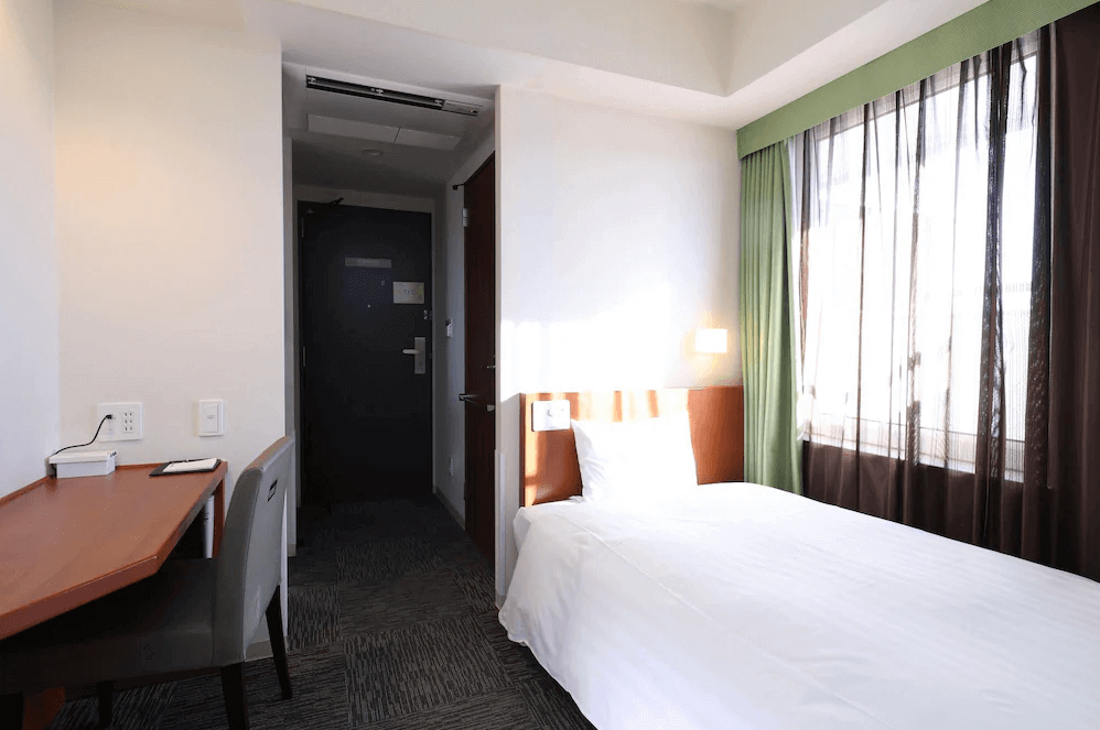 【北見住宿】Dormy Inn Kitami 北見飯店的單人房，設有書桌與大片窗戶採光，房內明亮溫馨，適合商務旅客與單人住宿。