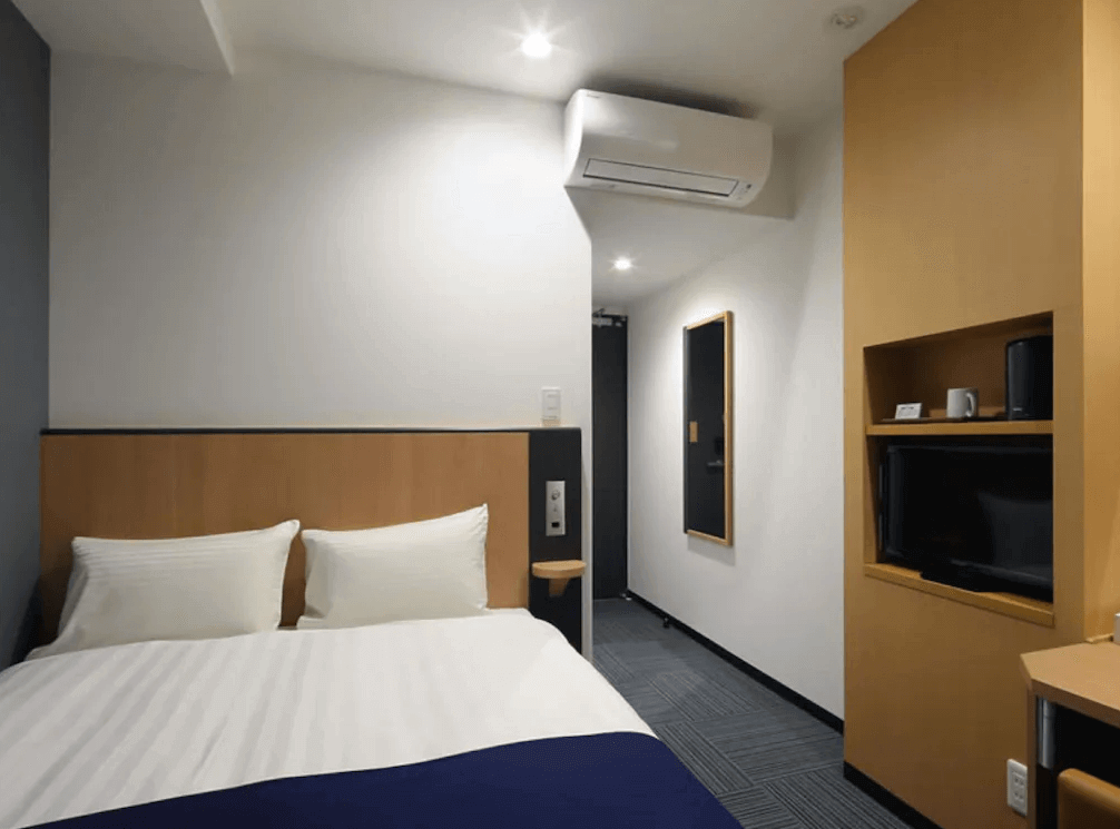 【奄美大島住宿】「Hotel West Court Amami 2 雙人房：木質元素結合現代設計，房內配置雙人床、空調、電視與書桌，空間緊湊但設備齊全。」