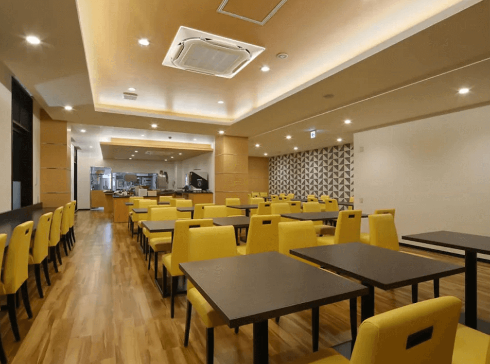 【奄美大島住宿】「Hotel West Court Amami 2 餐廳：整潔明亮的用餐空間，以黃色座椅與木質地板營造溫馨氛圍，適合享用早餐與輕食。」