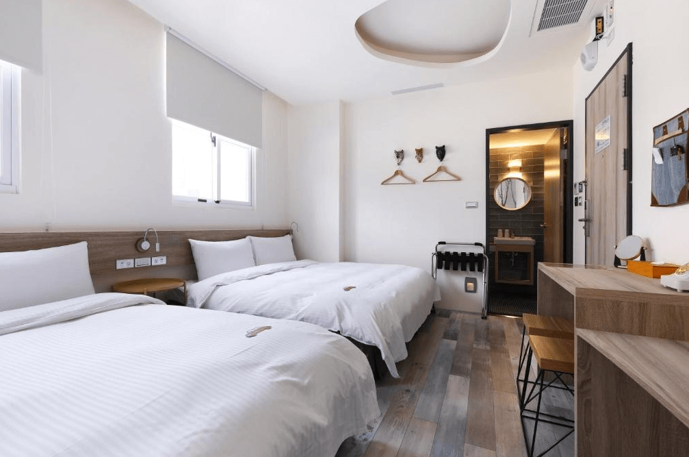 【台中火車站住宿】「MINI HOTELS 台中火車站館的雙床家庭房，採用清新簡約風格，設有木質書桌、牆面小掛飾與採光良好的窗戶，整體氛圍舒適自然。」