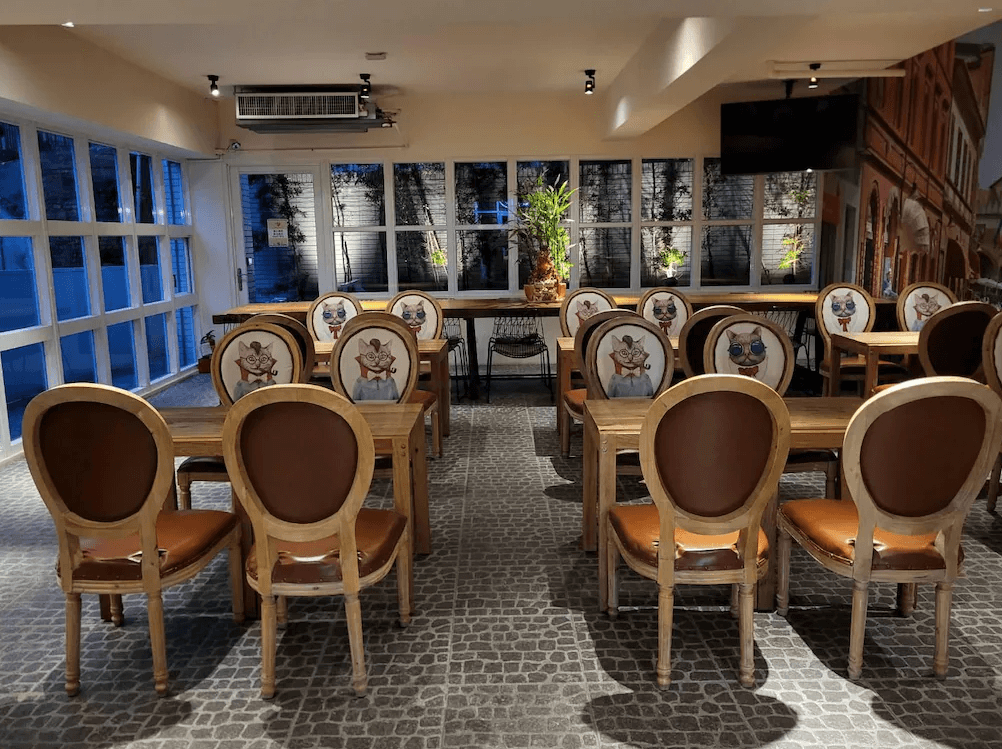 【台中火車站住宿】「MINI HOTELS 台中火車站館的用餐區，擺設帶有動物插畫圖案的椅子與木質桌面，大片窗景引入自然光，營造童趣又明亮的用餐氛圍。」