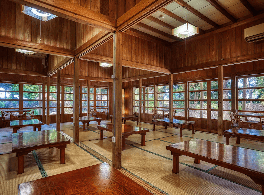 【讀谷村住宿】「Murasakimura 飯店園區內的傳統木造餐廳空間，採用大量木質梁柱與窗格設計，搭配榻榻米座位，展現濃厚的沖繩古民家風情。」