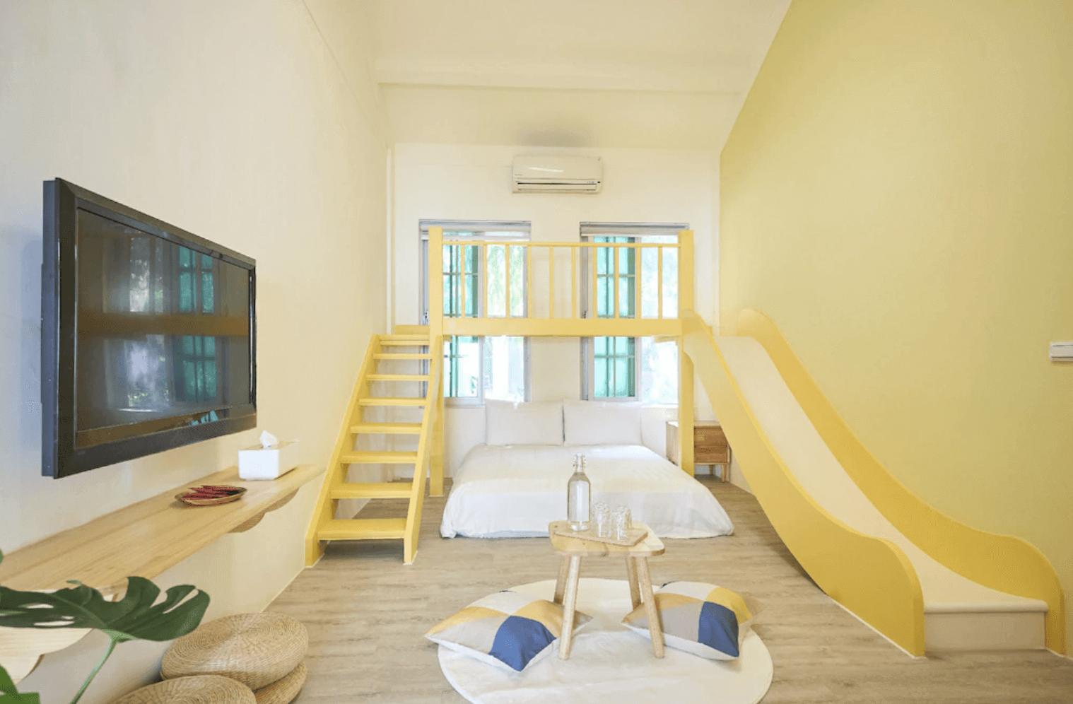 【東華大學民宿】「OwlStay故事所 綠舍」親子房型，明亮空間搭配鵝黃色牆面與可愛溜滑梯設計，樓中樓結構結合遊戲與休息區，提供小孩盡情玩樂的住宿體驗。