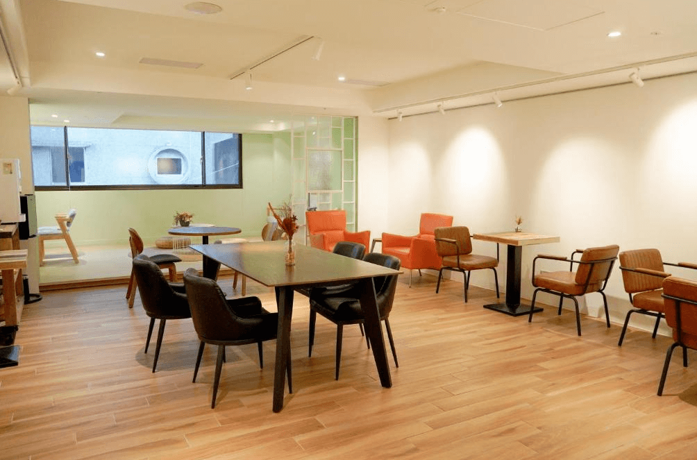 【台中火車站住宿】「old school 行旅・田中央旅店的公共休憩區，採用木地板與簡約家具，搭配大面窗戶及溫暖燈光，提供旅客舒適的閱讀與放鬆環境。」