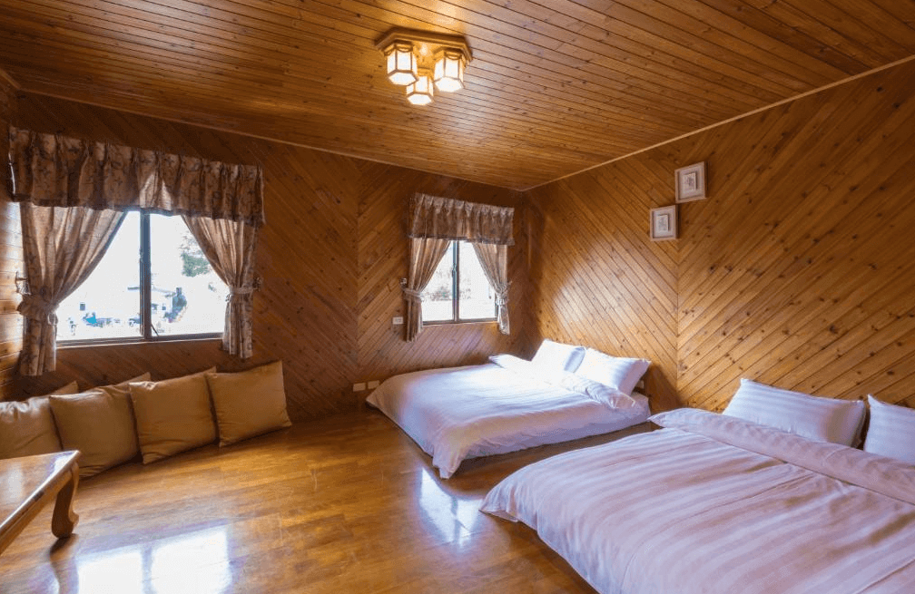 【瑞里住宿】「一品茶業民宿木屋家庭房｜全木質裝潢與溫暖光線，設有兩張雙人床與靠窗抱枕區，充滿自然溫馨感。」
