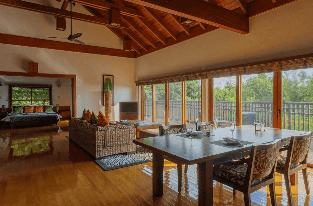 【屋久島住宿】「三卡拉羅久島Spa酒店 Sankara Hotel & Spa Yakushima 的豪華別墅房，設有開放式客廳與室內用餐區，四周被自然綠意包圍，擁有大量木質元素與舒適的生活空間。」