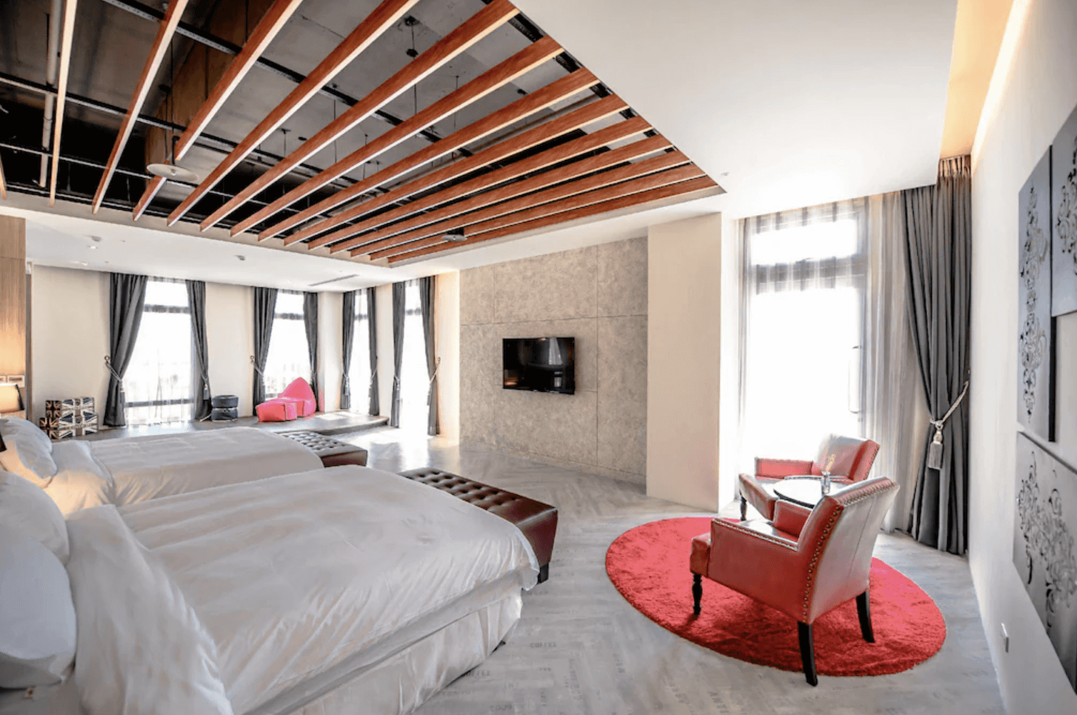 【宜蘭溫泉飯店】「九號溫泉旅店寬敞四人房，房內以挑高空間與木質天花板設計打造現代感，配置雙大床、紅色休憩沙發椅與大片落地窗，整體視覺明亮大器。」