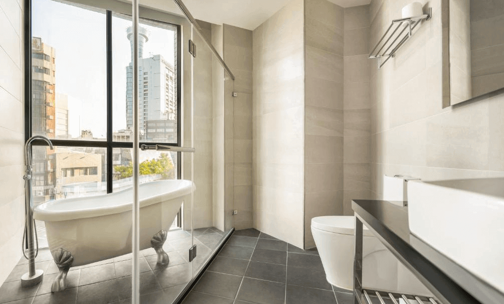 【台中火車站住宿】「凝萃文旅台中車站店的明亮景觀浴室，配置獨立復古腳爪浴缸、大面玻璃採光、淋浴與簡約梳洗檯面，整體以淺色系打造清新舒適風格。」