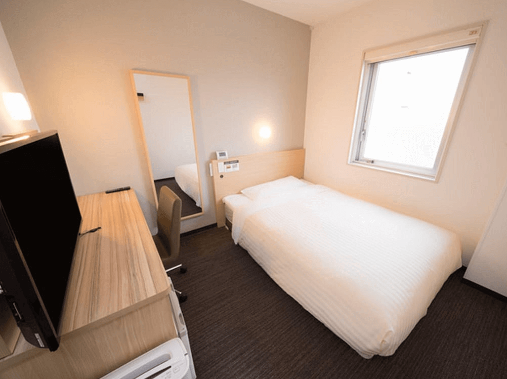 【北見住宿】北見超級酒店的單人房，設計簡約明亮，配置單人床與淺木色書桌，窗邊採光良好，整體空間乾淨整潔。