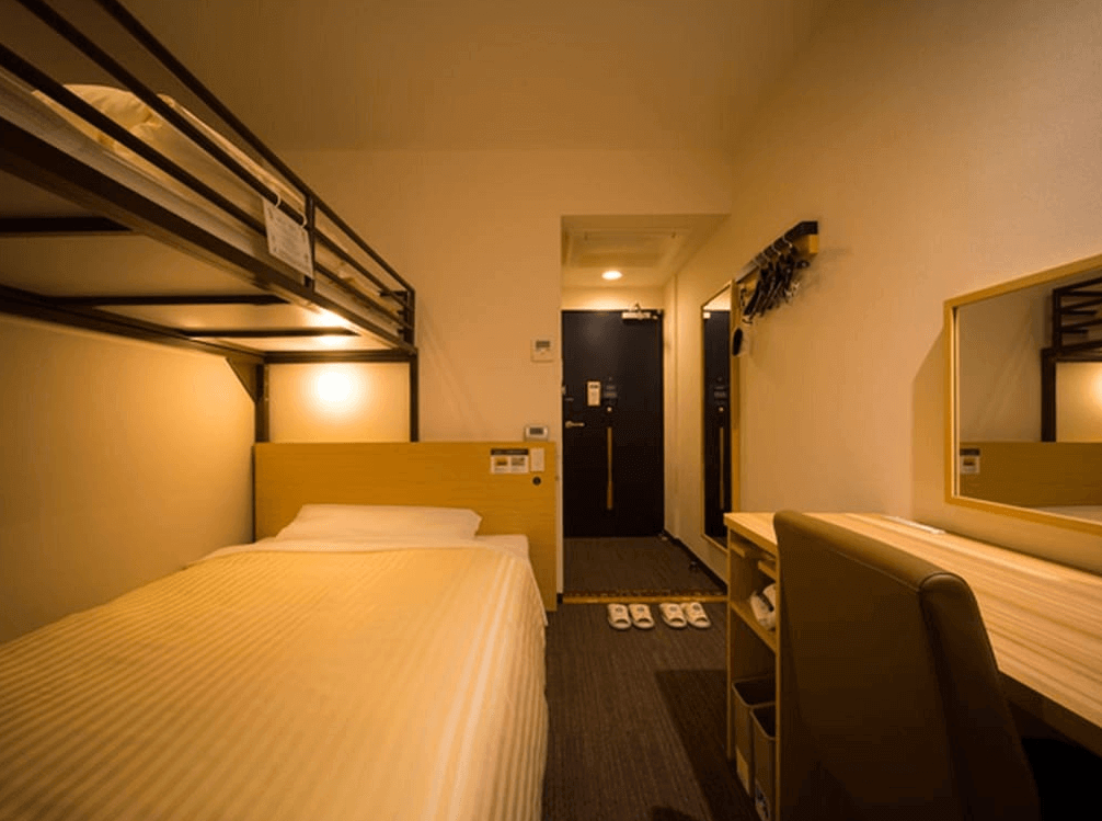 【北見住宿】北見超級酒店的上下舖家庭房，下層為單人床、上層為閣樓床鋪，搭配書桌與鏡面梳妝區，空間緊湊卻舒適實用。