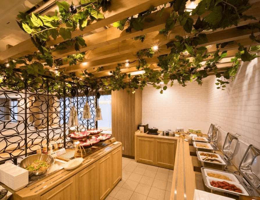 【北見住宿】北見超級酒店的自助早餐區，木質裝潢搭配綠色植栽裝飾，擺滿多樣料理與沙拉吧，營造溫馨自然的用餐氛圍。
