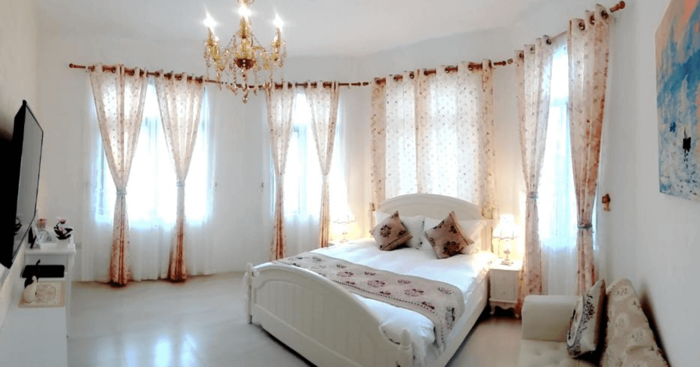 【東華大學民宿】花蓮吉哈克莊園民宿典雅雙人房，米白色牆面與花布窗簾營造歐式浪漫氛圍，搭配古典吊燈與柔和採光，呈現明亮舒適的住宿空間。