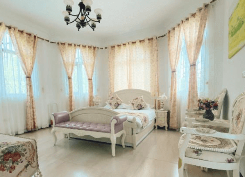 【東華大學民宿】花蓮吉哈克莊園民宿豪華雙人房，設有歐風雕花家具與柔粉色沙發，大片窗簾與自然光線讓房間明亮寬敞，展現浪漫宮廷風格。