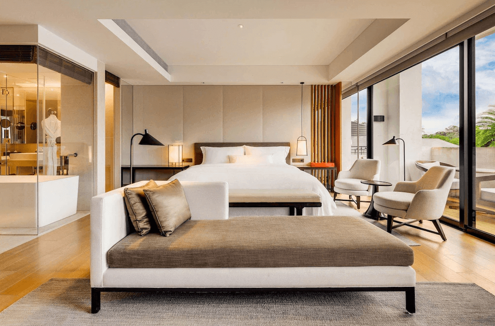 【大溪住宿】「大溪笠復威斯汀度假酒店 — 豪華套房內景，大片落地窗引入自然光線，配有沙發、閱讀椅與玻璃浴室設計，營造寬敞明亮的度假氛圍。」
