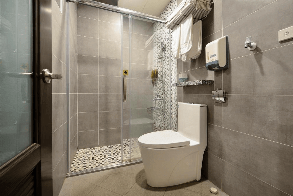 【大溪住宿】大溪老城四季行館好客民宿 浴室空間，灰色磁磚搭配乾濕分離玻璃拉門，配置白色馬桶與花灑淋浴設備，整潔明亮。