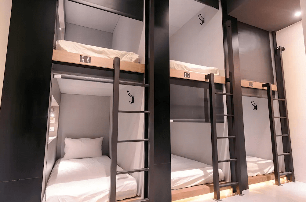 【台中火車站住宿】「奇異果快捷旅店-站前二店的背包客膠囊房型，上下舖設計整齊排列，黑白極簡風格，並設有上下爬梯與個人小燈。」