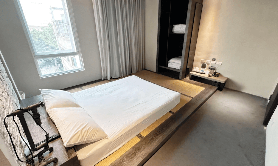 【台中火車站住宿】「奇異果快捷旅店-站前二店的和風榻榻米房型，低矮床鋪、木質平台與大片窗景，呈現簡約溫馨的住宿氛圍。」