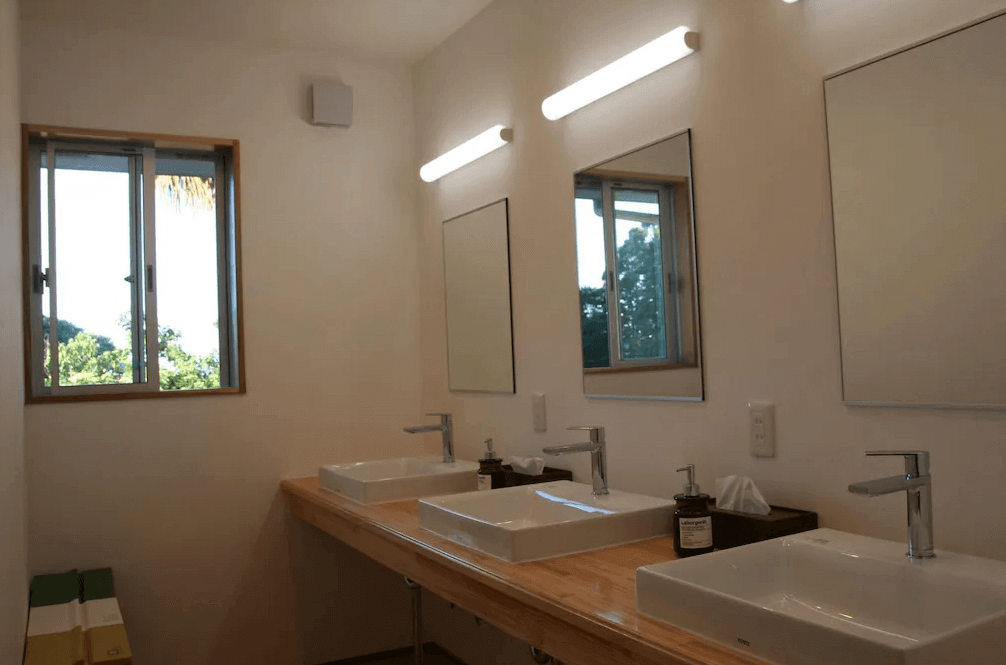 【屋久島住宿】「屋久之宿田口旅館（Yakunoyado Taguchi）整潔明亮的公共洗手台區，設有三座方形檯面洗臉盆與大鏡子，簡約日式風格搭配自然光。」
