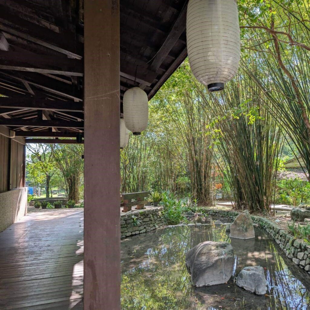 【山杉青旅】「山杉青旅周邊景點——礁溪森林風呂入口周邊景色，木造亭子搭配懸掛紙燈籠，旁邊是小水池與岩石造景，被綠竹與樹木圍繞，展現靜謐自然的日式庭園氛圍。」