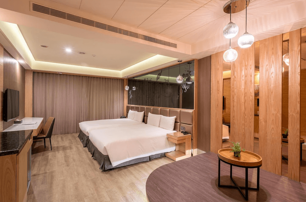 【台中火車站住宿】「承攜行旅台中自由館的雙床房型空間，採用暖色木質裝潢與鏡面隔間，搭配垂吊燈飾與寬敞動線，整體風格現代明亮。」