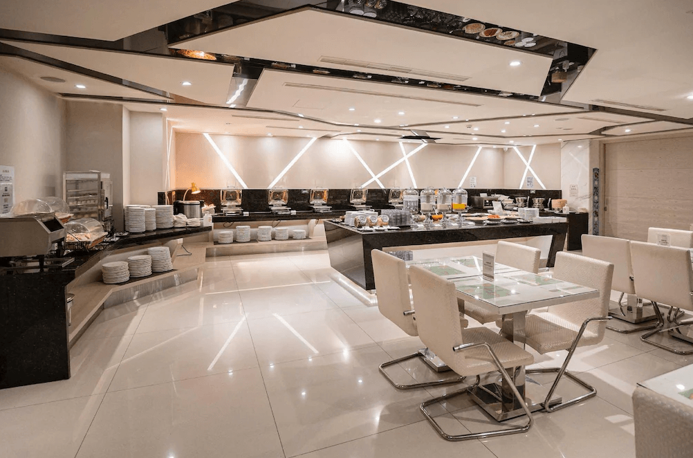 【台中火車站住宿】「承攜行旅台中自由館的早餐餐廳環境，設有自助式取餐吧台與整潔明亮的用餐座位區，採白色與黑色大理石風格設計，呈現高雅舒適氛圍。」