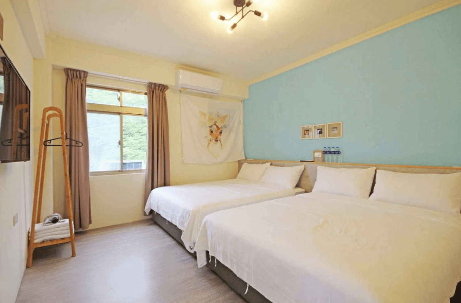 【綠島寵物友善住宿】「拾光旅行－綠島民宿雙人房，牆面為清新藍色，床舖整潔舒適，牆上掛有熱帶風情掛布與英文字樣裝飾，採光明亮。」