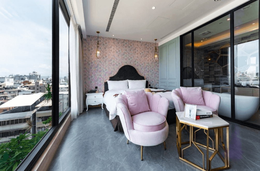 【台中火車站住宿】「挪威森林台中文創館的景觀房，設有粉嫩系沙發椅與高雅白色床鋪，大面落地窗可欣賞城市景色，房內以花磚牆與金屬吊燈妝點，呈現夢幻法式風格。」