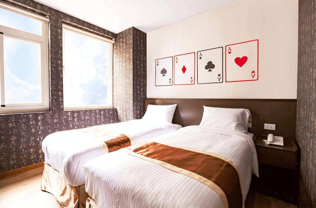 【台中火車站住宿】「撲克商旅日光雙床房，牆面以四張撲克牌 A 作為主題，搭配大面採光窗與暖色調床鋪布置。」