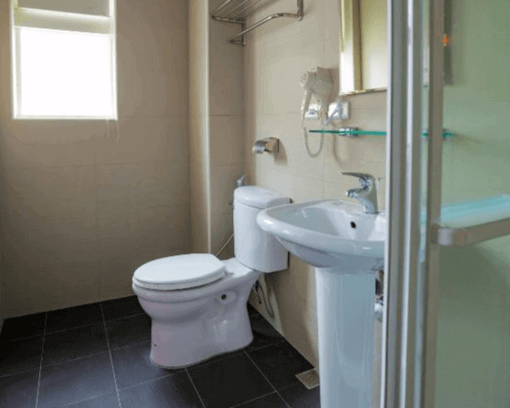 【台中火車站住宿】「撲克商旅浴室空間，配有沖洗間、馬桶、洗手台與自然採光窗，設計簡潔明亮。」