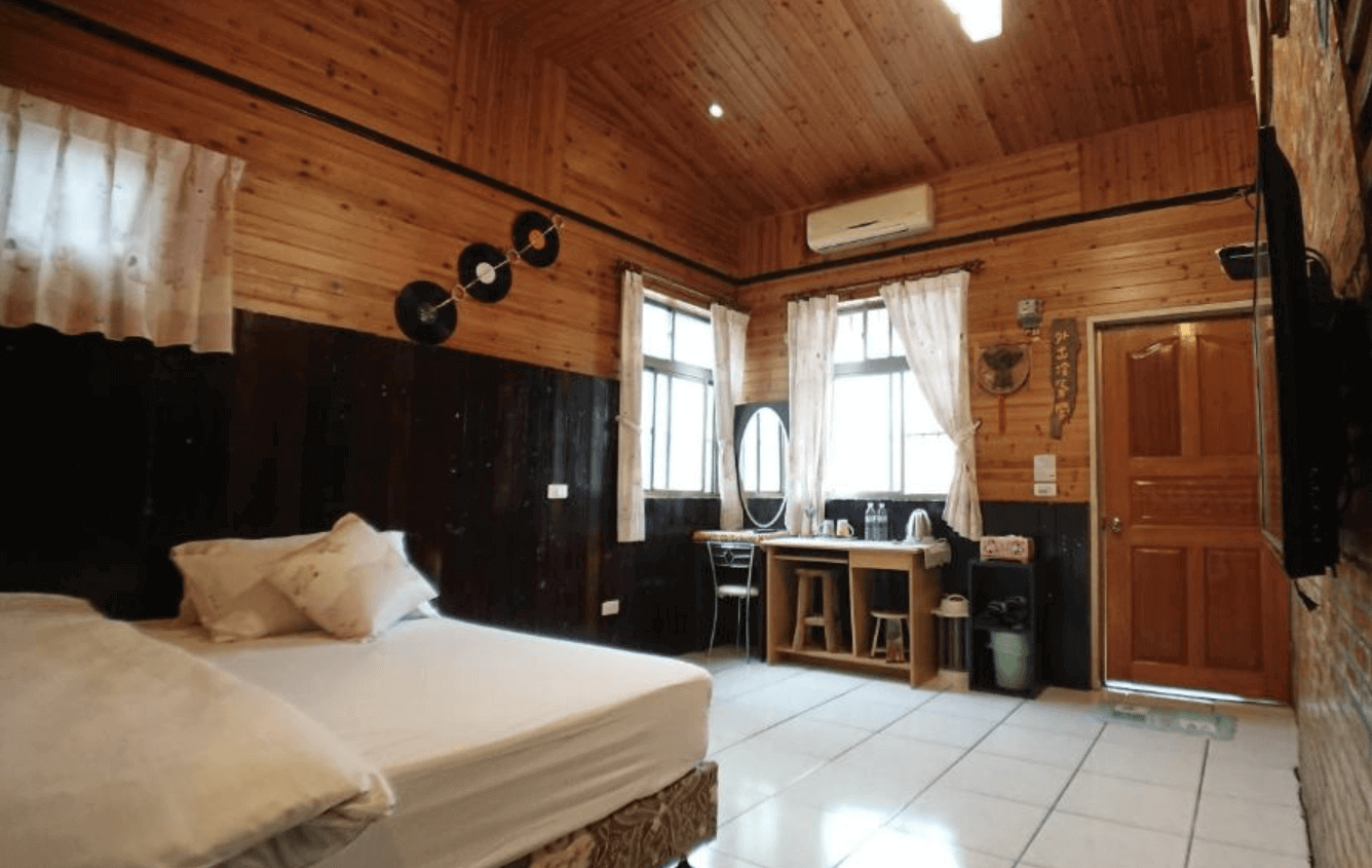 【東華大學民宿】「東華八號民宿」雙人房，整體以原木裝潢打造，牆面掛有黑膠唱片裝飾，窗邊設有梳妝桌與熱水壺，空間溫馨樸實、充滿鄉村氣息。