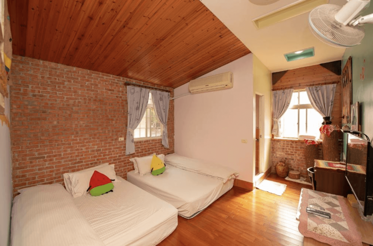 【東華大學民宿】「東華八號民宿」四人房，磚牆與木質天花設計營造懷舊風格，房內設有兩張大床與可愛抱枕，陽光灑入房內，氛圍溫暖舒適。