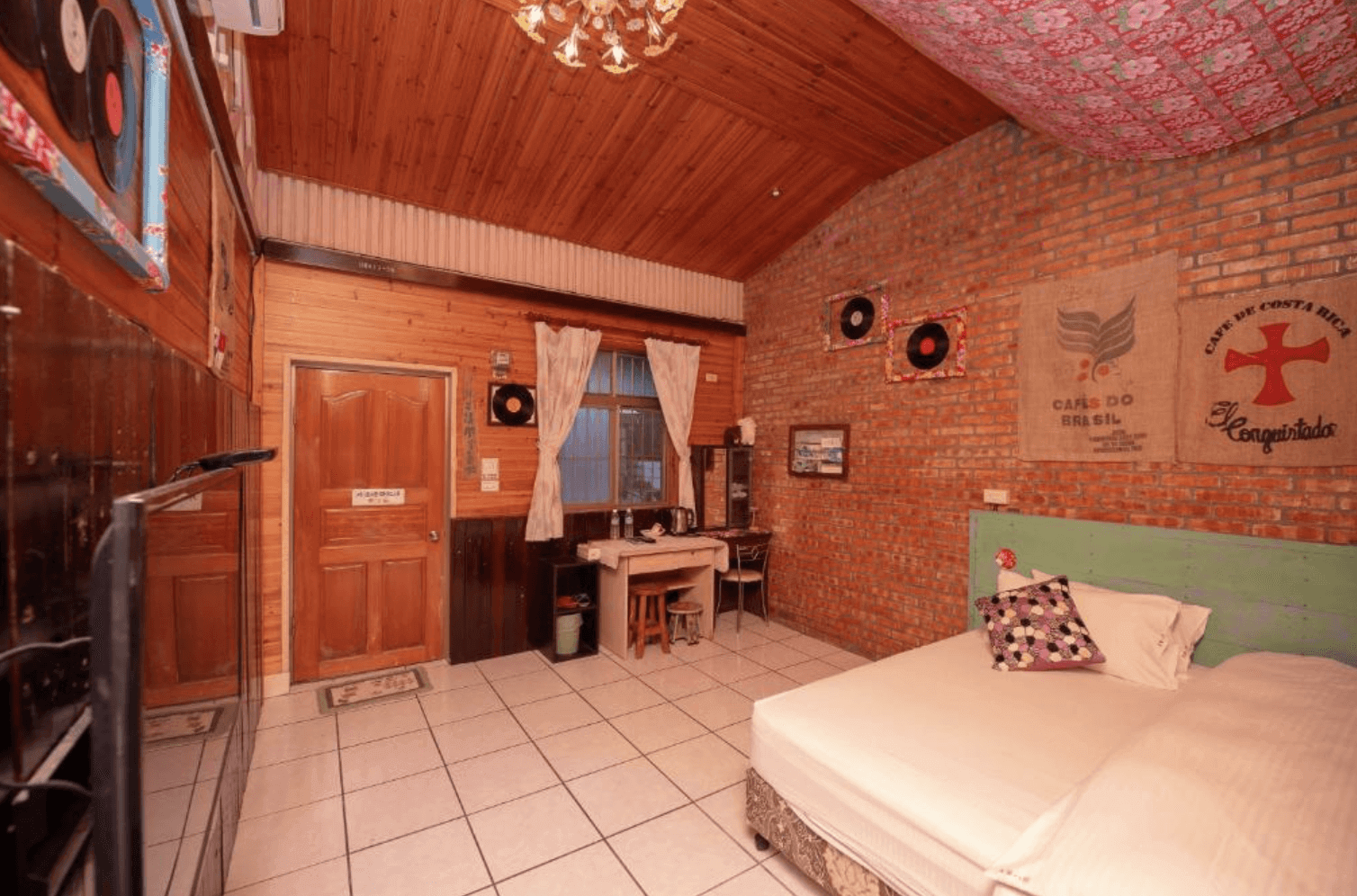 【東華大學民宿】「東華八號民宿」雙人房，結合紅磚牆與木質裝潢的復古風格，牆上掛有唱片與咖啡麻布袋裝飾，室內整潔明亮，散發懷舊鄉村氛圍。