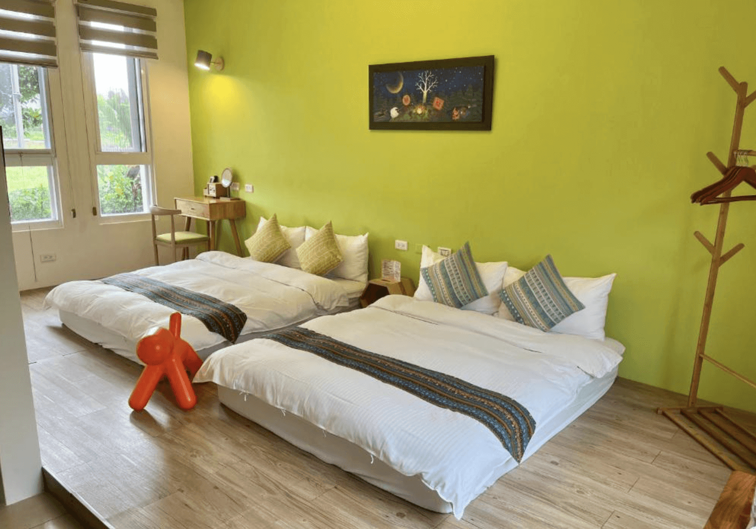 【東華大學民宿】梅匠‧花蓮寵物友善民宿家庭四人房，亮綠色牆面搭配溫暖木質地板，兩張雙人床整齊擺放，房內採光良好，擁有溫馨自然的親子氛圍。