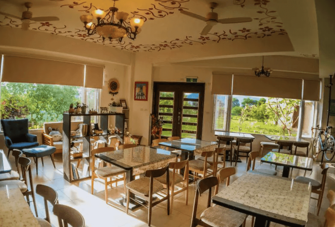 【東華大學民宿】梅匠‧花蓮寵物友善民宿早餐用餐區，大片落地窗引入自然光，內部以溫潤木質桌椅與手繪天花板裝飾，營造明亮放鬆的鄉村風格。