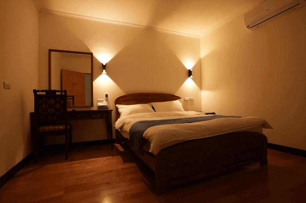 【大溪住宿】樂木居 河岸行館 溫馨雙人房，木質地板搭配柔和燈光，設有梳妝桌與古典椅，整體空間簡約典雅、氛圍溫暖。