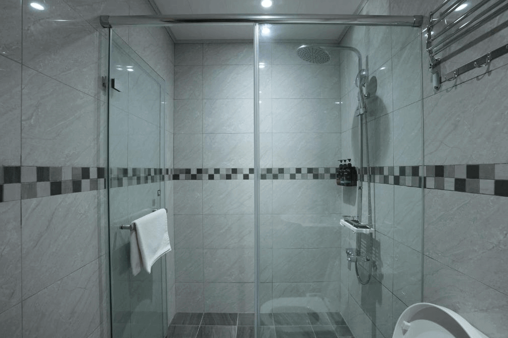 【大溪住宿】樂木居 河岸行館 浴室空間，灰白磁磚搭配乾濕分離設計，設有花灑淋浴與玻璃拉門，整潔明亮。