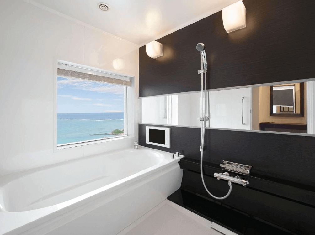 【讀谷村住宿】「沖繩殘波岬度假村－美居的觀海浴室，浴缸旁設有大面窗戶，可將蔚藍海景盡收眼底，搭配簡潔黑白對比設計，營造靜謐奢華的沐浴空間。」