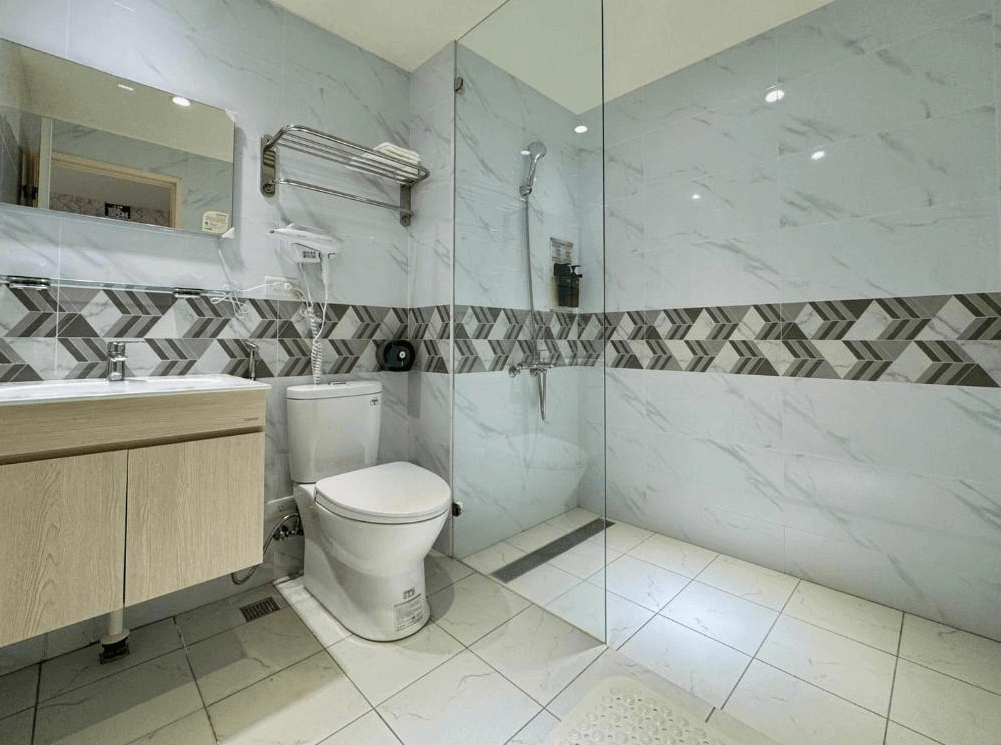 【大溪住宿】湧山水民宿 浴室空間，白色大理石紋牆面搭配幾何線條拼磚設計，乾濕分離淋浴間整潔明亮，配備齊全。