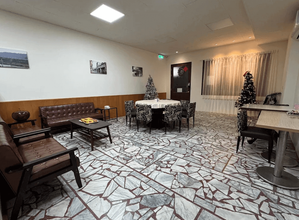 【大溪住宿】湧山水民宿 公共交誼廳，設有皮沙發與圓桌餐區，地板以馬賽克磚拼花設計，布置聖誕樹與窗簾營造節慶氛圍，空間寬敞明亮。