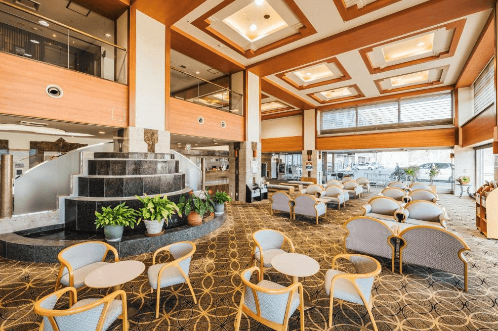 【北見住宿】溫根湯溫泉美肌之湯宿大江本家的寬敞大廳，挑高空間與溫暖燈光設計，中央設有黑色階梯式水景造景，整體氛圍典雅大方。