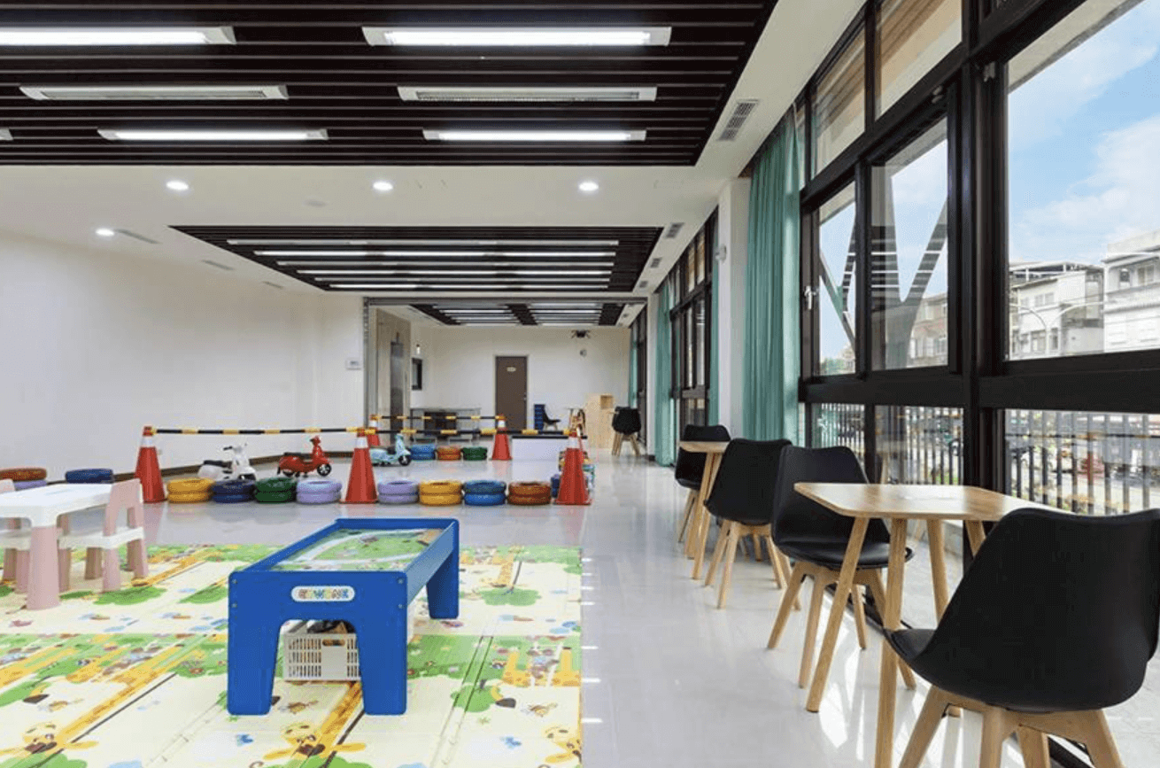 【東華大學民宿】「童樂會親子民宿」兒童遊戲室，設有地墊、玩具桌、滑步車與安全護欄，大片玻璃窗採光良好，另備有家長休憩區桌椅，兼顧親子互動與放鬆空間。