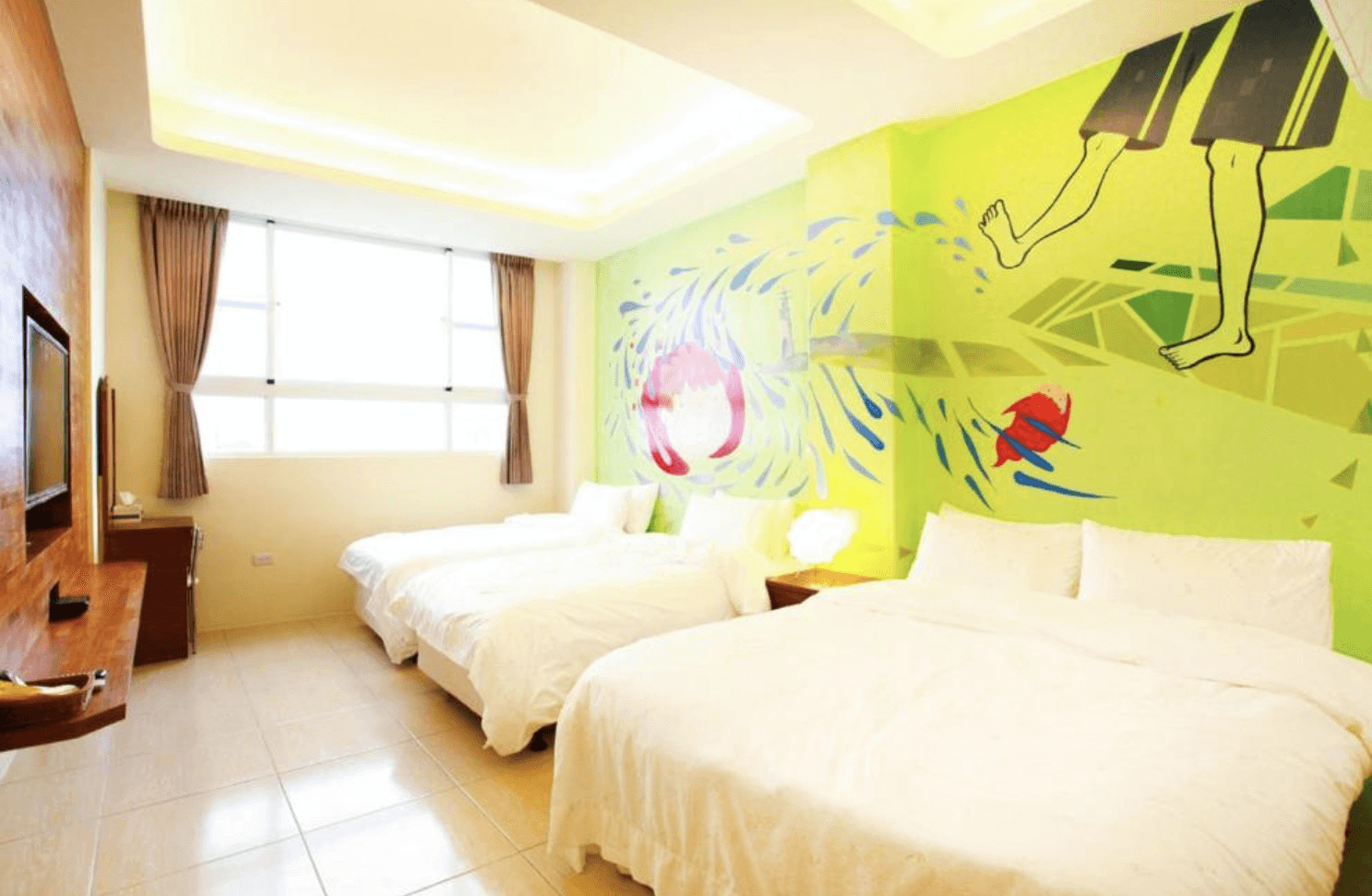 【綠島寵物友善住宿】「綠島美人魚民宿的綠色海洋主題四人房，牆面繪有玩水與魚群彩繪圖案，整體空間明亮寬敞，搭配兩張大床與柔和燈光，充滿活潑度假氛圍。」