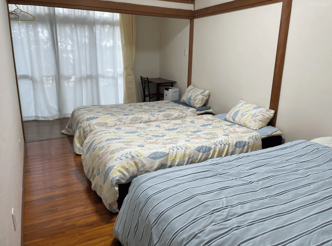 【奄美大島住宿】「花海house（Kami House）客房：房內設有三張單人床，採木質地板與簡約風格，搭配柔和自然光線的溫馨住宿空間。」