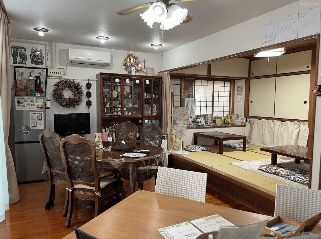 【奄美大島住宿】「花海house（Kami House）公共用餐與休憩空間：結合木質家具、展示櫃及和室座位區，呈現溫暖的家庭式民宿氛圍。」