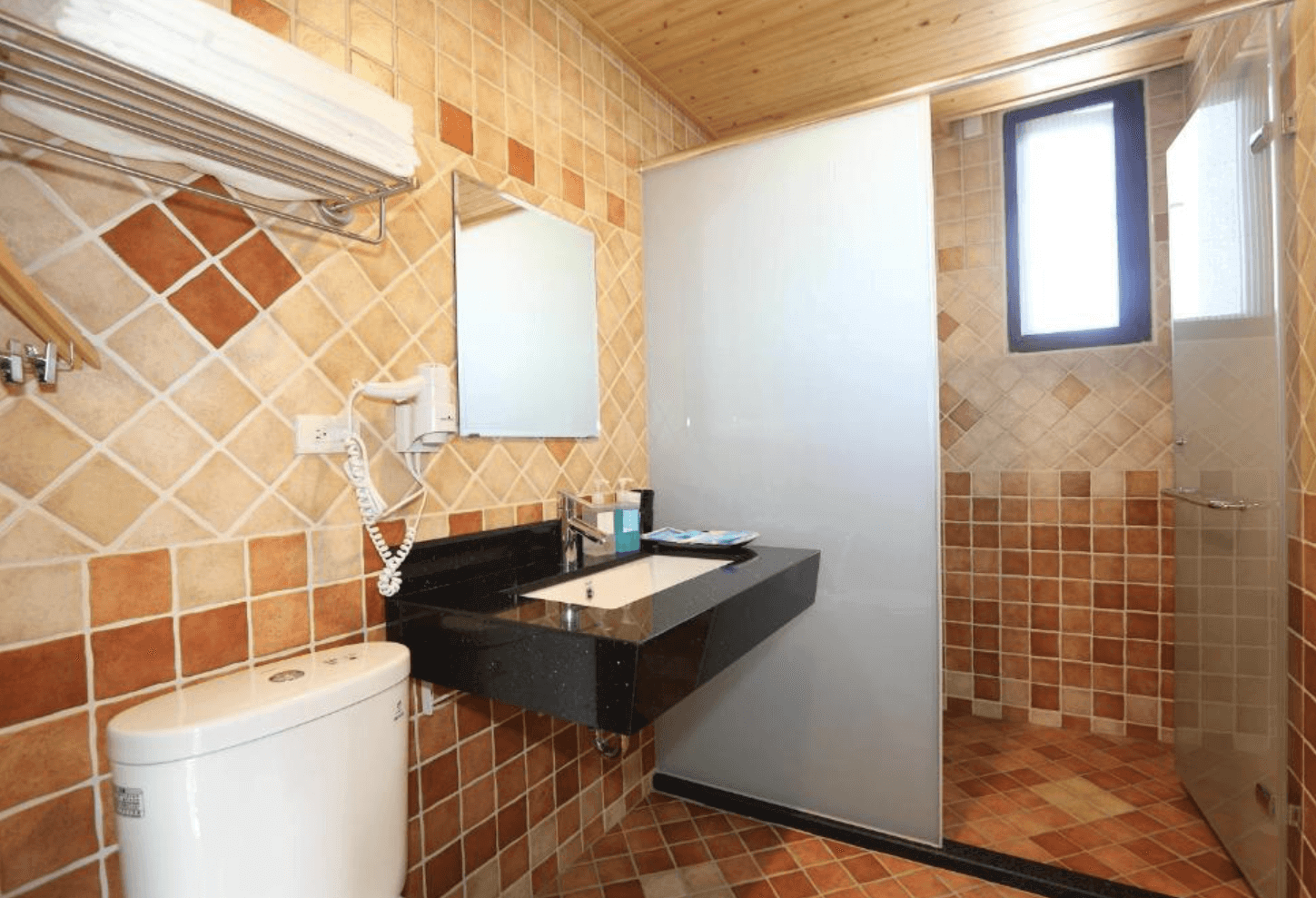【東華大學民宿】「花綠蒂庭園民宿」浴室空間，採用橘黃色系磁磚與黑色洗手台設計，乾濕分離、備有吹風機與盥洗用品，環境明亮乾淨。