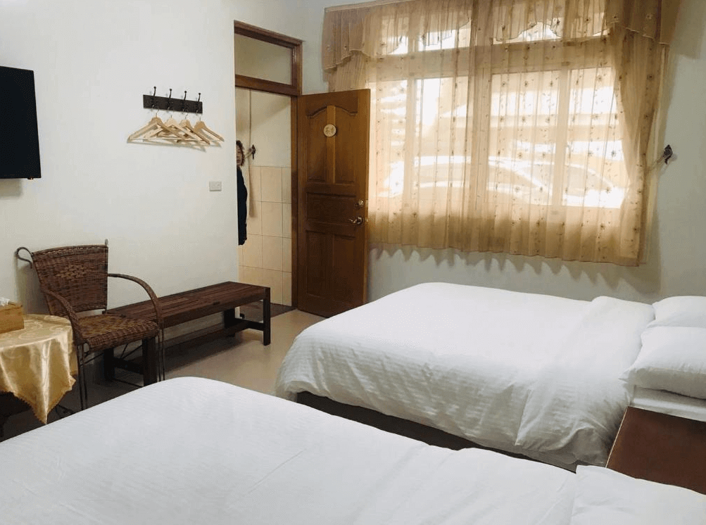 【瑞里住宿】「茗軒竹民宿雙人房｜房間寬敞明亮，設有兩張雙人床、藤椅與衣架，窗簾柔和透光，營造溫馨氛圍。」