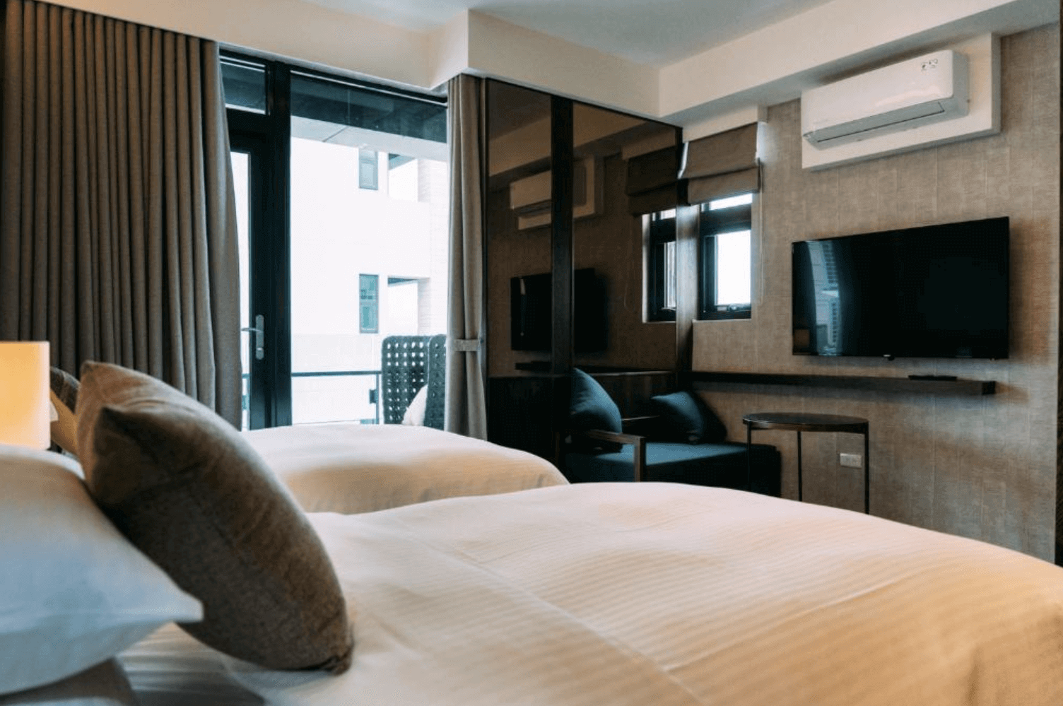 【宜蘭溫泉飯店】「藏闊渡假會館」— 精緻雙人房，大片落地窗引入自然採光，搭配木質家具與簡潔線條，房內配置電視、沙發座椅與柔軟寢具，呈現清爽舒適的住宿環境。