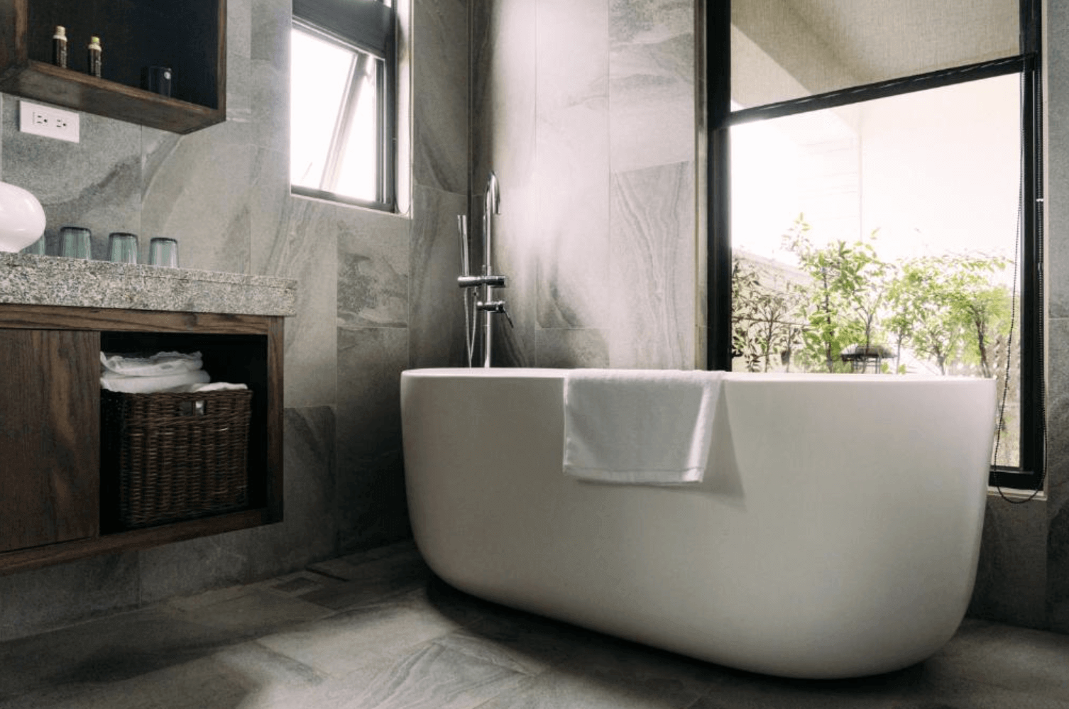 【宜蘭溫泉飯店】「藏闊渡假會館」— 房內獨立浴室設有大型獨立浴缸，周圍以石紋磁磚與木質收納櫃打造質感空間，窗外綠意景觀營造放鬆泡澡氛圍。