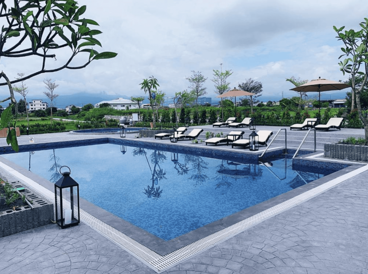 【宜蘭溫泉飯店】「藏闊渡假會館」— 戶外游泳池環境，以藍色水池搭配周邊綠意與躺椅，視野遼闊，可眺望山景，是適合放鬆度假的戶外休閒空間。